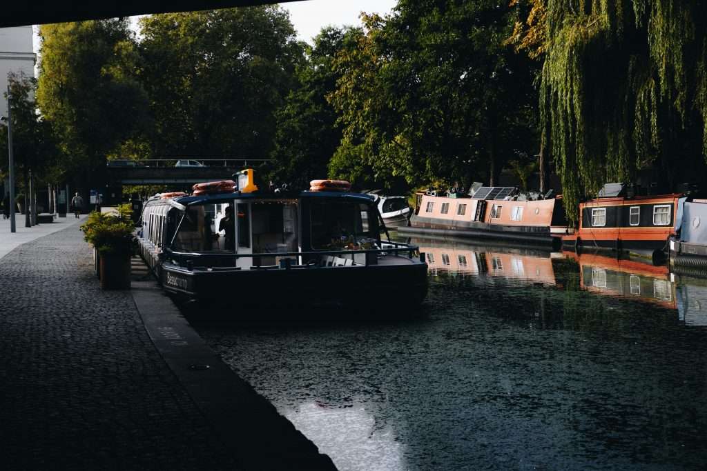 Explore the serene beauty of London's Regent's Canal with colorful barges and leafy surroundings.