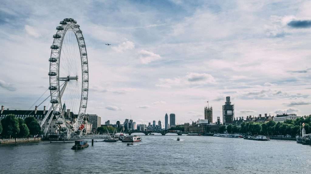 Scenic view of the London Eye on the River Thames with clear blue skies and city skyline.
