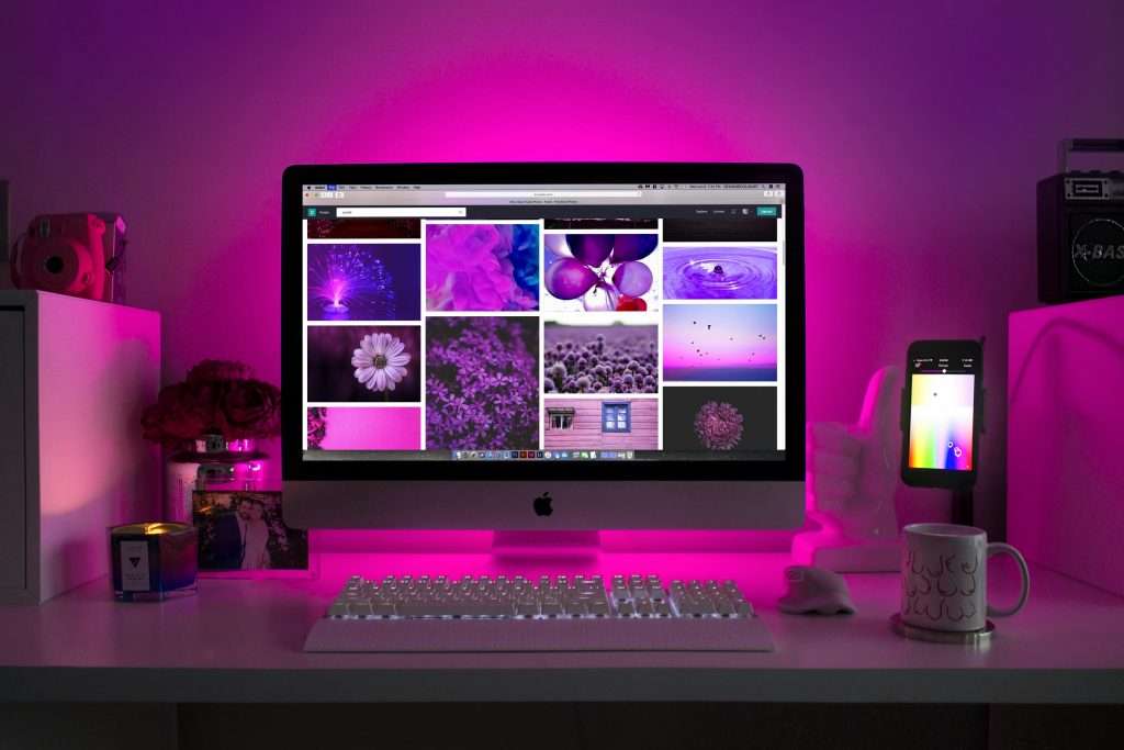 Modern desk setup with neon lighting and a desktop computer displaying colorful images. Web development
